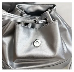 Close-up of magnetic snap closure and drawstring on silver metallic bucket bag