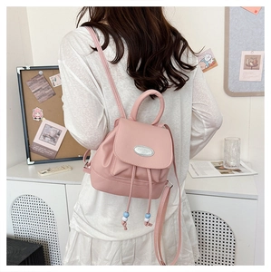 Detail of pink PU leather mini backpack with beaded drawstring and metal logo plate