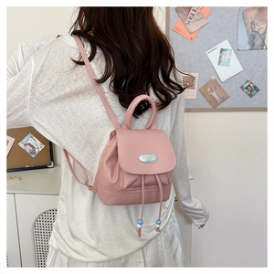 Detail of light pink mini PU leather backpack with drawstring closure and silver brand plate
