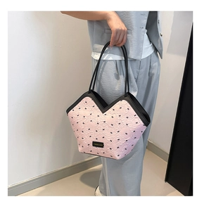Detailed close-up of pink tote bag featuring black bow patterns and V-shaped opening