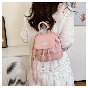 Detail of pink faux leather backpack featuring a magnetic flap and adjustable straps