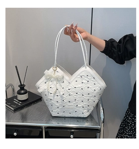 Detail of white tote bag featuring black bow patterns and elegant pearl lace pendant
