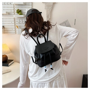 Detail of a black mini leather backpack with drawstring closure and chic beaded accents