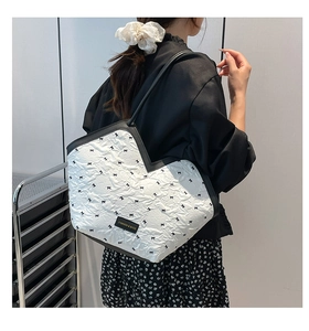 Shoulder shot of large quilted tote bag with black bows and leather trim detail