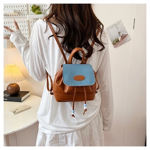 Detail of mini bucket backpack with brown leather, blue denim flap and drawstring beads