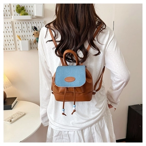 Detail view of mini backpack with brown faux leather and blue denim patchwork cover