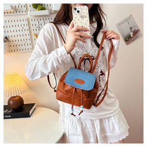 Detail of mini bucket backpack featuring blue denim flap and brown leather with colorful beads