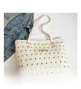 Macro view of white floral embossed tote bag with black bow embroidery and gold hardware