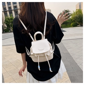 Detail of white leather mini backpack with drawstring closure and decorative beads