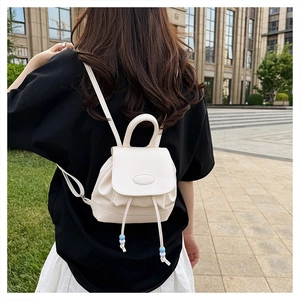 Dettaglio mini zaino in pelle PU bianco crema con chiusura a coulisse e nappe di perline