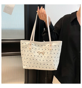 Close-up of white tote bag featuring black rabbit print and gold bow detail