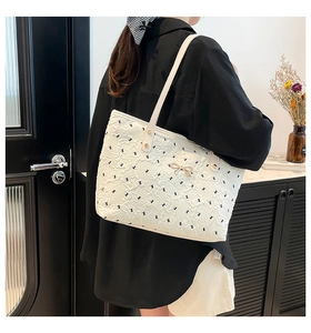 Detail of white tote bag with black bow patterns and elegant golden metal clasp