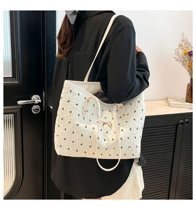 Detail of white textured tote bag featuring bunny prints and a golden bow accent
