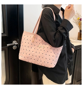 Detail of pink textured tote bag with black pattern and gold bow metal buckle on a shoulder