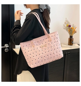 Detail of pink quilted tote bag featuring black cartoon prints and golden bow buckle