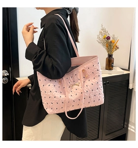 Pink quilted tote bag with black print and gold bow detail shown on female model