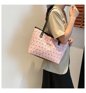Close-up of pink pleated tote bag featuring a golden bow buckle and black leather strap