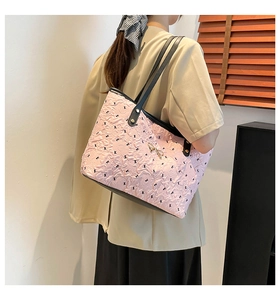 Detail of pink quilted tote bag with gold bow and black leather straps on a shoulder