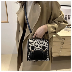 Detail of leopard print crossbody bag with black leather trim and gold hardware accents