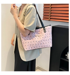 Quilted pink tote bag with black straps and golden bow detail in a modern interior
