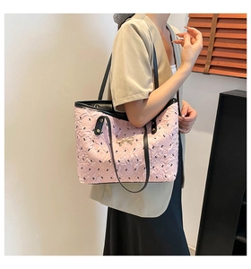 Close-up of pink textured tote bag featuring black rabbit prints and golden bow clasp