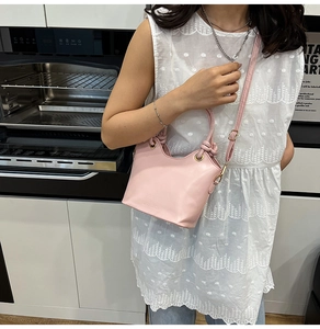Détail du sac seau rose avec poignée nouée et bandoulière réglable porté par le mannequin