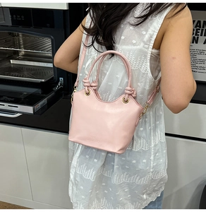 Dettaglio della borsa a secchiello in pelle rosa con manico in corda e occhielli dorati