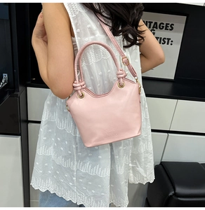 Dettaglio borsa a secchiello in ecopelle rosa con manico intrecciato e anelli metallici
