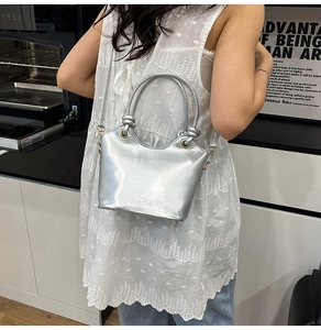 Borsa a secchiello metallizzata argento con manico a nodo e logo a rilievo su modella
