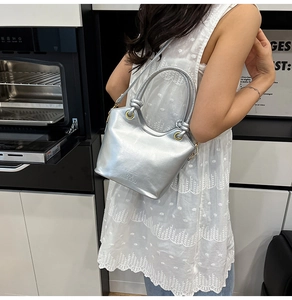 Gros plan d'un sac seau argenté métallisé avec poignées nouées et finition moderne