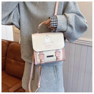Détail d'un sac bandoulière rose et blanc avec imprimé ours et finition en cuir PU texturé