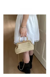 Κοντινή λήψη της μπεζ υφαντής τσάντας clutch με χρυσή μεταλλική λαβή και αλυσίδα