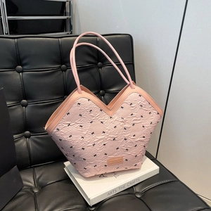 Light pink tote bag with black bow patterns and V-neck opening on a leather sofa