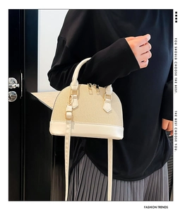 Detail of beige straw shell bag with cream leather trim and gold-tone hardware