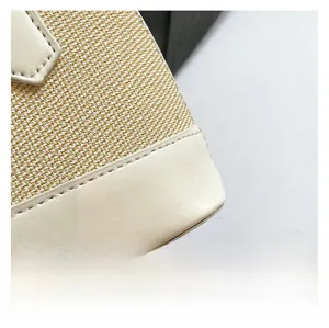 Detailed macro view of woven canvas texture and white leather stitching on the shell bag
