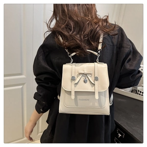 Détail d'un petit sac à dos blanc crème avec nœud et pendentif cœur sur modèle