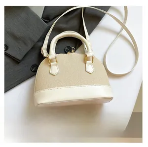 Close-up of shell-shaped straw and white leather patchwork handbag with gold zippers