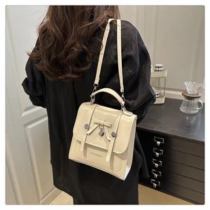 Detailed view of cream crossbody bag with bow accent and heart charm on model