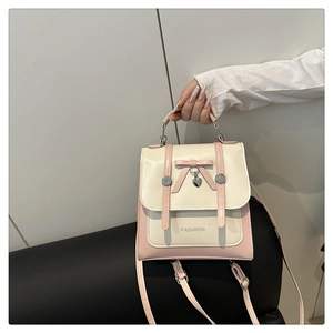 Detailed view of pink and beige patchwork bag with bow decoration and heart charm