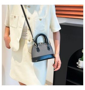 Detail of grey woven fabric texture and black leather straps on a mini shell bag