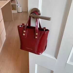 Retro wine red patent leather tote bag with gold hardware shown on a white door