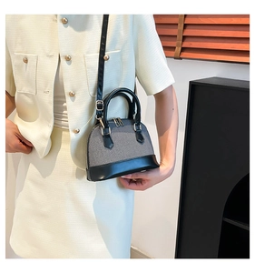 Detail of shell-shaped crossbody bag featuring textured fabric and leather splicing