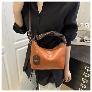Detail of pleated orange handbag with dark brown handle and golden fashion chain
