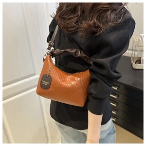 Detail of light brown pleated leather hobo bag with cloud handle and fashion tag