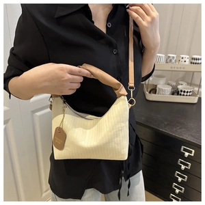 Detail of pleated beige bucket bag with brown leather handle and fashion tag