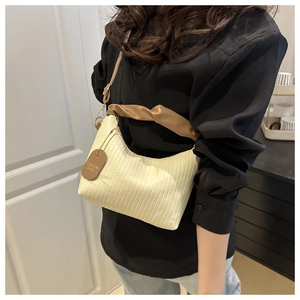 Detail of pleated crossbody bag featuring brown knotted strap and fashion tag detail