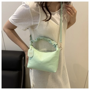 Detail of mint green pleated handbag with curved handle and fine vertical textures