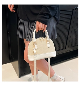 Detail of cream straw shell bag showing leather handles and woven texture on model