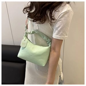 Detail of mint green pleated hobo bag with a scrunched handle and circular logo tag