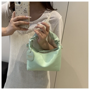Macro shot of the mint green striped texture and ruched handle on the trendy shoulder bag